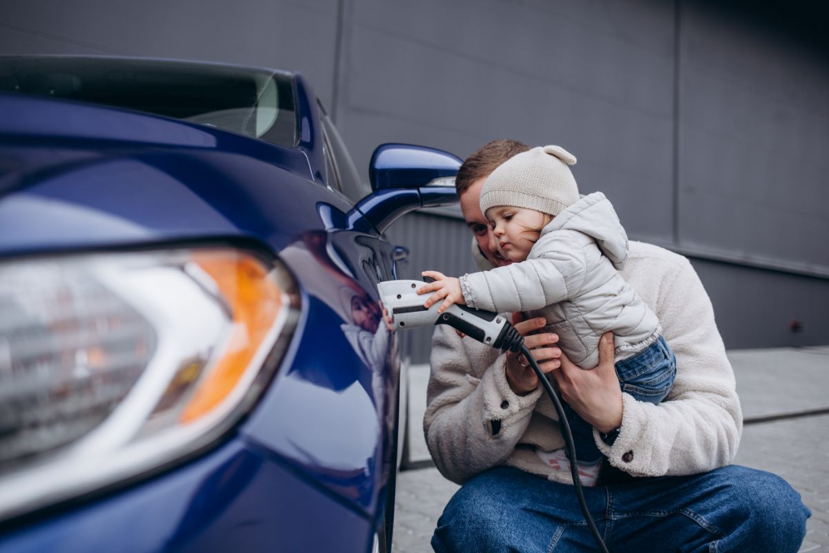 Father shows daughter how to charge electric vehicle.