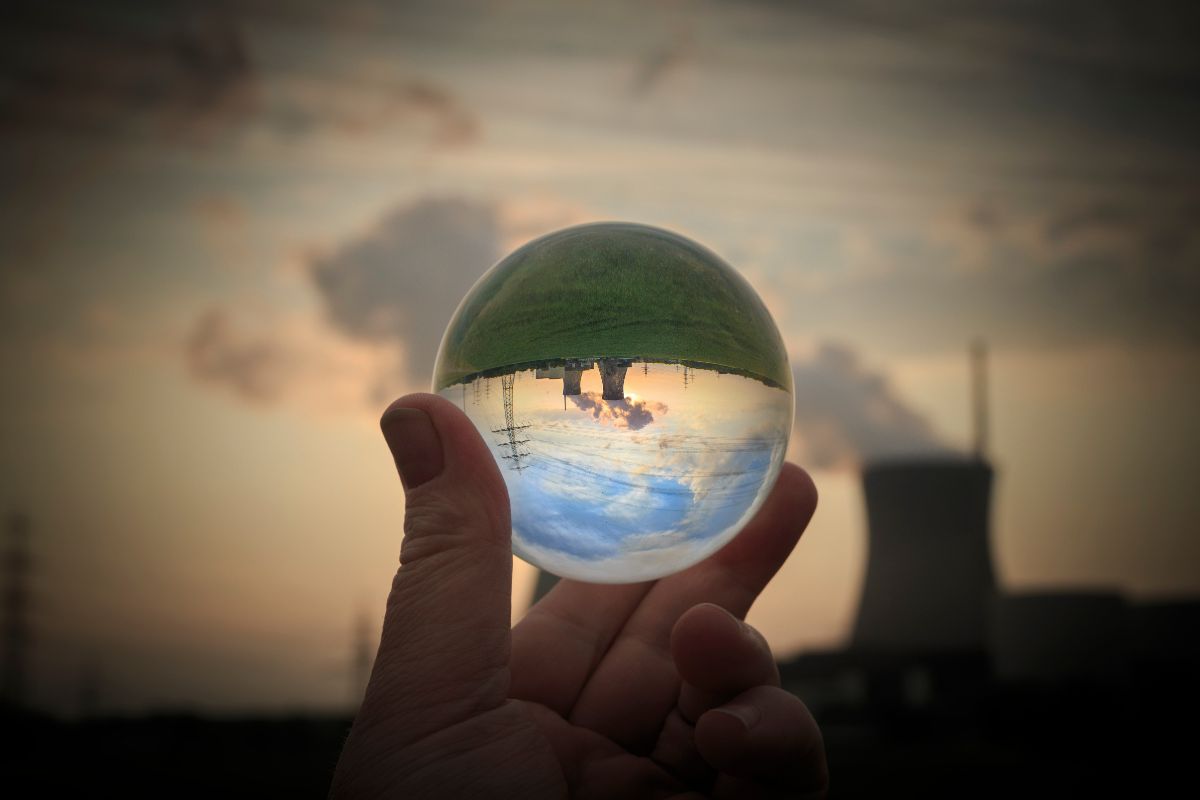 Hand holding glass globe, reflecting nuclear plant.
