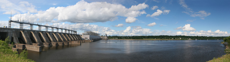 Landscape photo of a large hydro electric dam in eastern Canada, under a partly cloudy sky and a view of the dam waters