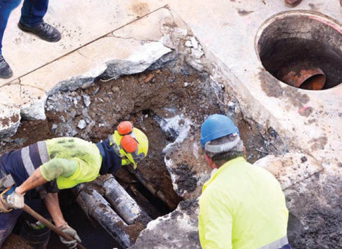 Ouvriers du bâtiment creusant autour d’un tuyau enterré